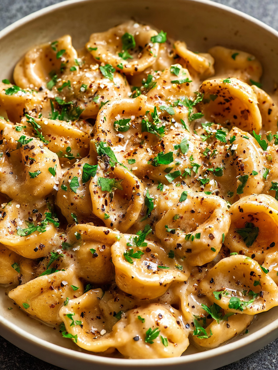 Ein Bild von einer Schüssel mit Pasta, die mit Parmesan und Kräutern garniert ist.